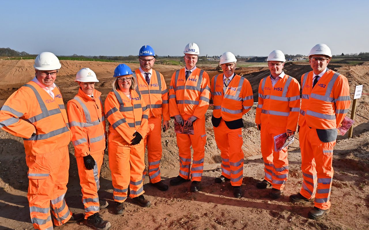 A group of people in hi-vis suits and hard hats standing on the HS2 building site.