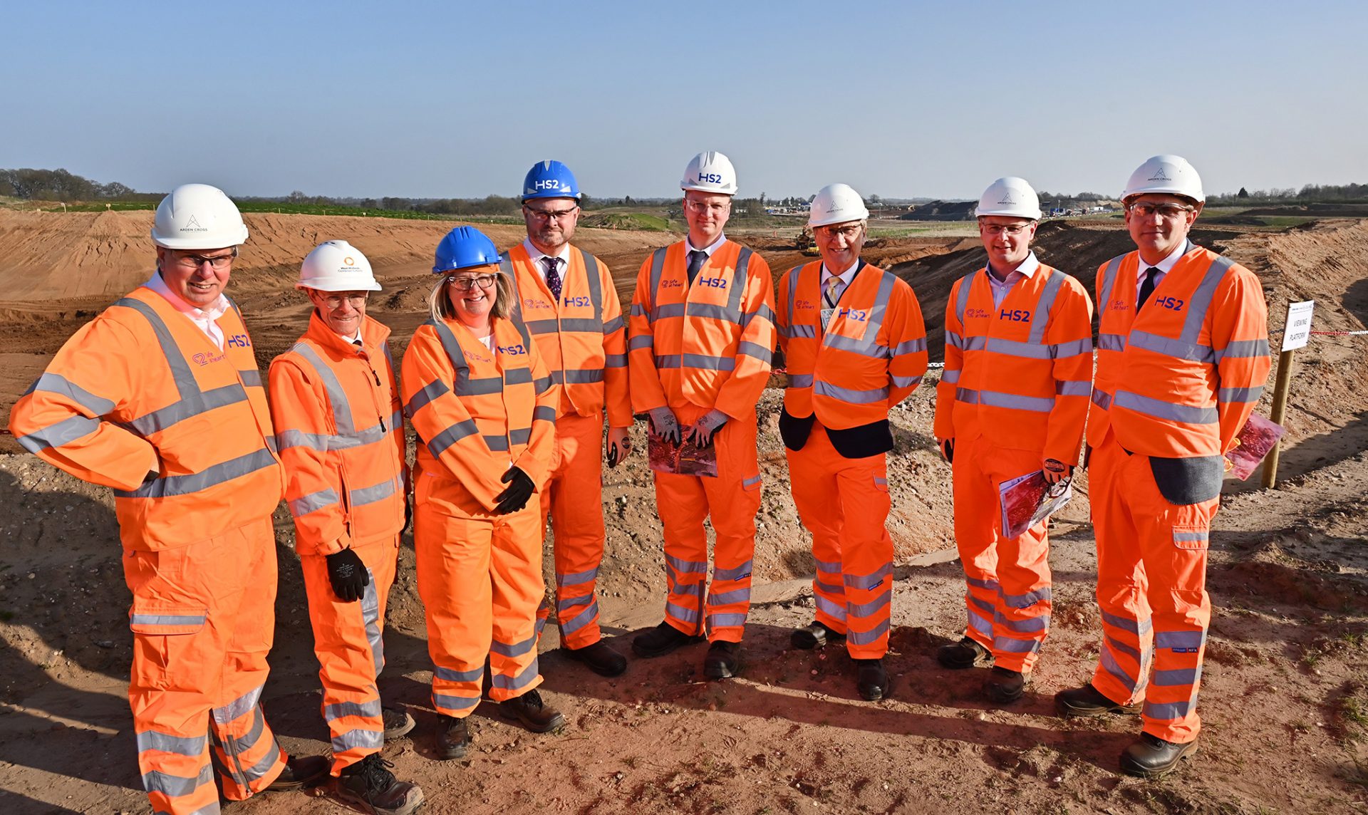 A group of people in hi-vis suits and hard hats standing on the HS2 building site.